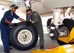 Two man replace a main landing gear tire of a plane.jpg