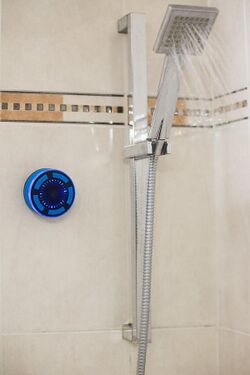 a shower speaker attached to the wall of a shower with a suction cup
