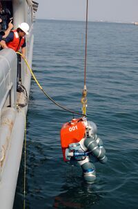 The ADS 2000 suit is lowered into the sea from the side of a ship