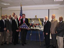 Senator Mark Warner congratulating the Chilean Miners Rescue Support Team, including Levine, while holding a folded American flag