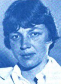 A white woman with short dark hair cut in bangs, wearing a white collared shirt; photo is printed in blue ink in original source