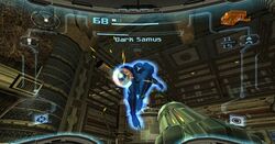 View of a futuristic looking room; an enemy in a big, futuristic-looking black powered suit with a helmet, large, bulky, and rounded shoulders charges the firearm on the right arm. The player's weapon (a large cannon) is visible in the corner of the screen. The image is a simulation of the heads-up display of a combat suit's helmet, with a crosshair surrounding the enemy and two-dimensional icons relaying game information around the edge of the frame.