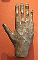 A detailed metallic hand with the fingers up and covered with a Himyaritic inscription.