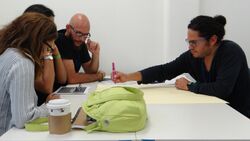 A group of writers gather at a desk to collaborate