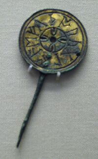 Pin with a large round head, on which eleven runic letters are carved in a circle around the edge