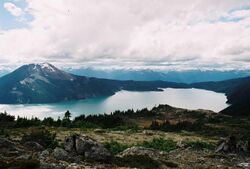 A mountain rising above a lake in the foreground with glaciated mountains in the background.