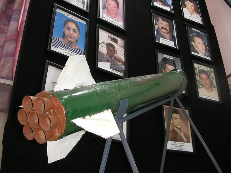 File:Sderot - A Qassam rocket is displayed in Sderot town hall against a background of pictures of residents killed in rocket attacks.jpg