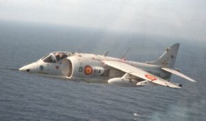 A Harrier flies over an aircraft carrier below.