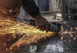 Bright sparks fly as a man grinds a piece of metal
