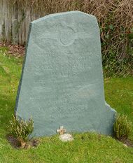 Irregular green gravestone standing in a grassy churchyard