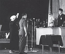 Suharto is sworn in, standing in front of other military officers