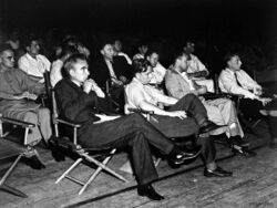 A group of men in shirtsleeves sitting on folding chairs